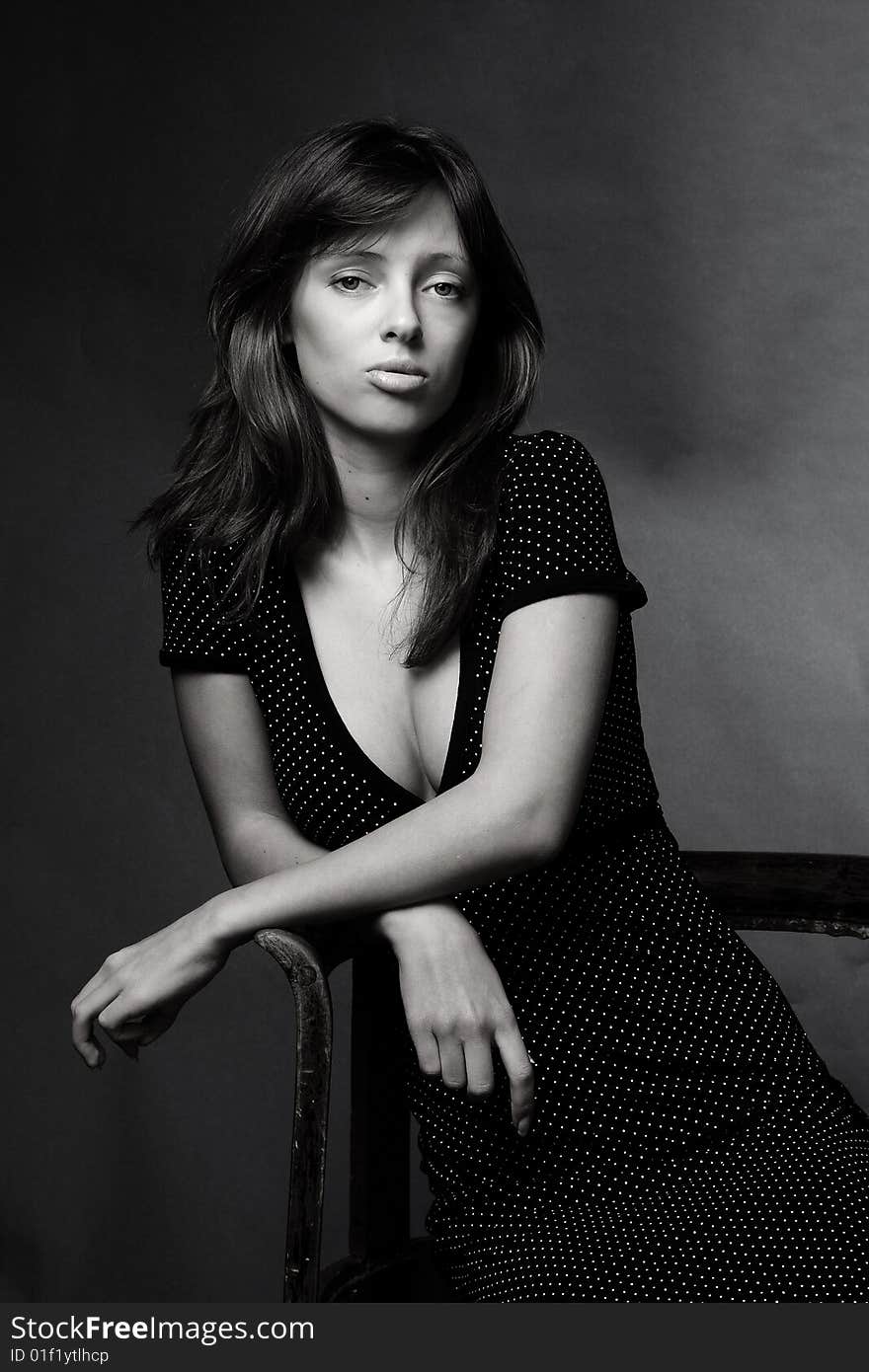 Black and white portrait of an attractive young woman sitting on a chair. Black and white portrait of an attractive young woman sitting on a chair