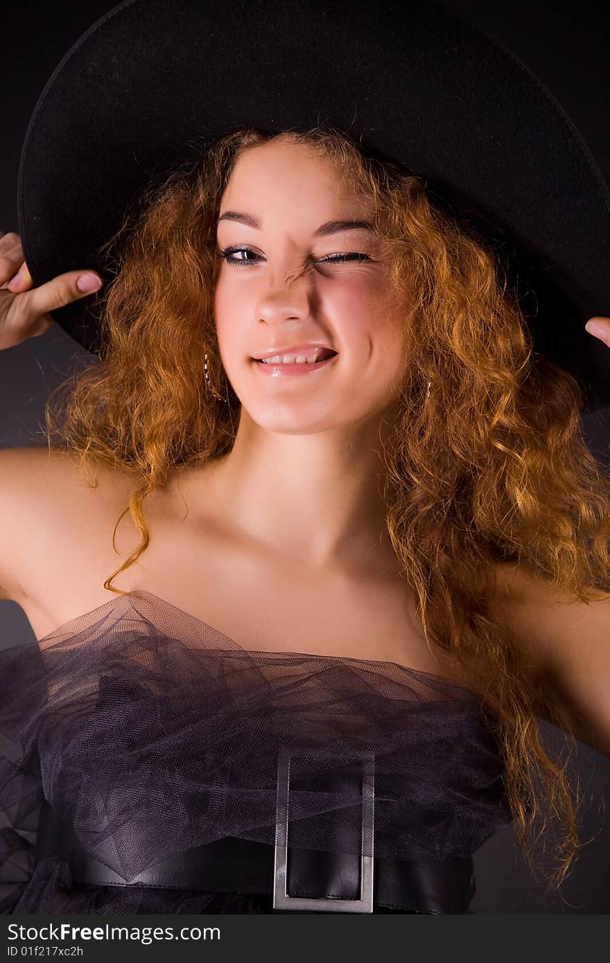 Winking red-haired girl in hat, studio shot