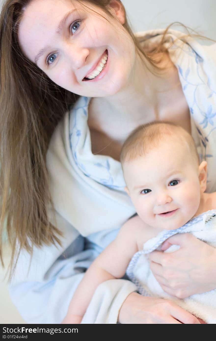 Young smiling mother with her baby after bath