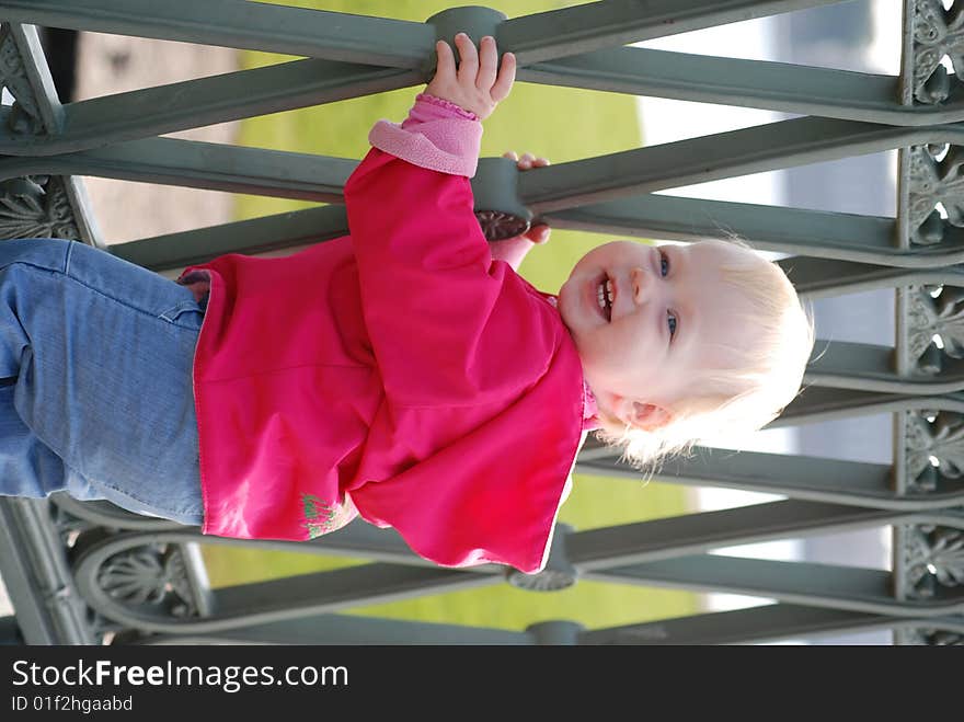 Little girl near the grate of bridge