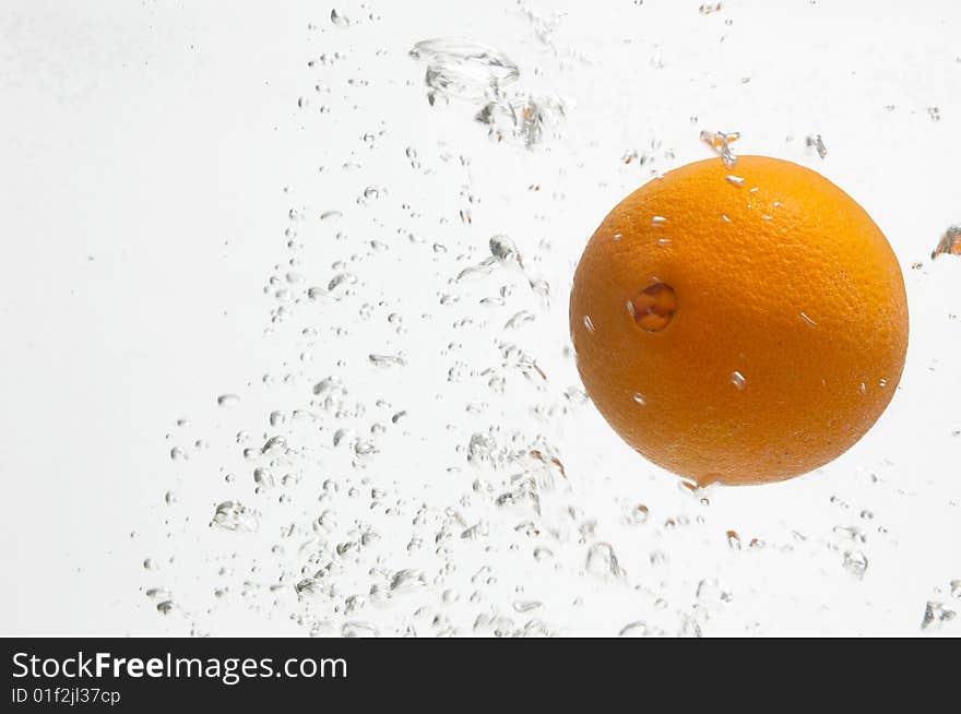 Fresh and juicy orange is dropped into water. Fresh and juicy orange is dropped into water.