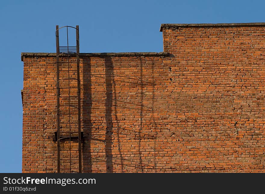 The metal staircase on the brick wall of building. The metal staircase on the brick wall of building