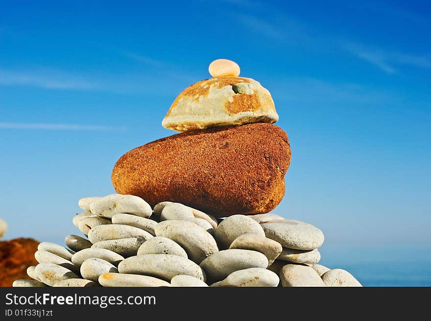 The big red stone at top of a pyramid at the sea in the summer. The big red stone at top of a pyramid at the sea in the summer