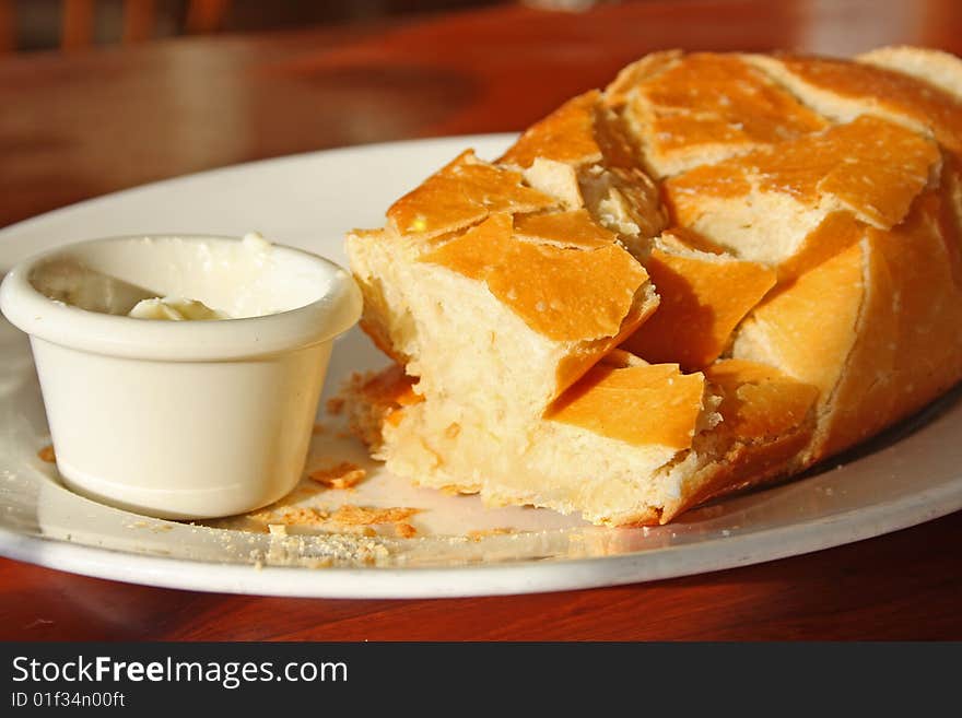 A plate of fresh butter and a crusty loaf of bread warm from the oven. A plate of fresh butter and a crusty loaf of bread warm from the oven.