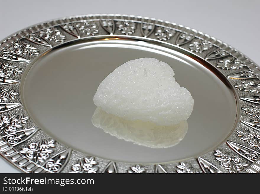 White heart shaped candle on a silver salver. White heart shaped candle on a silver salver