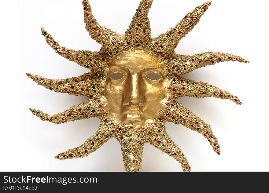 Golden mask of sun decorated with tinsel