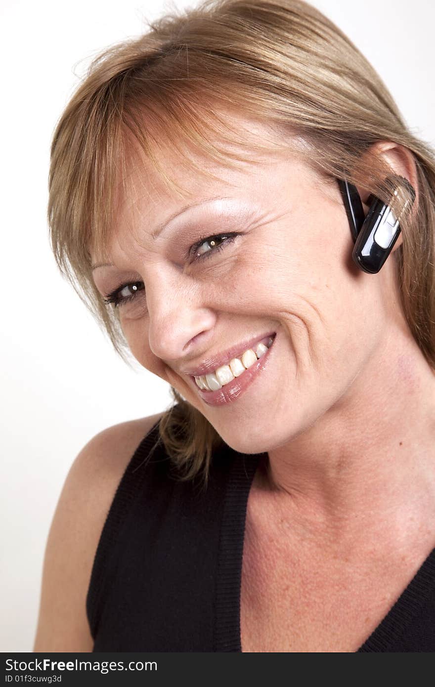 A beautiful mature woman with a wireless earpiece and head tilted to side. A beautiful mature woman with a wireless earpiece and head tilted to side