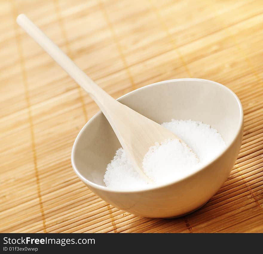 Bowl on a bamboo mat filled with bath salt. Bowl on a bamboo mat filled with bath salt.