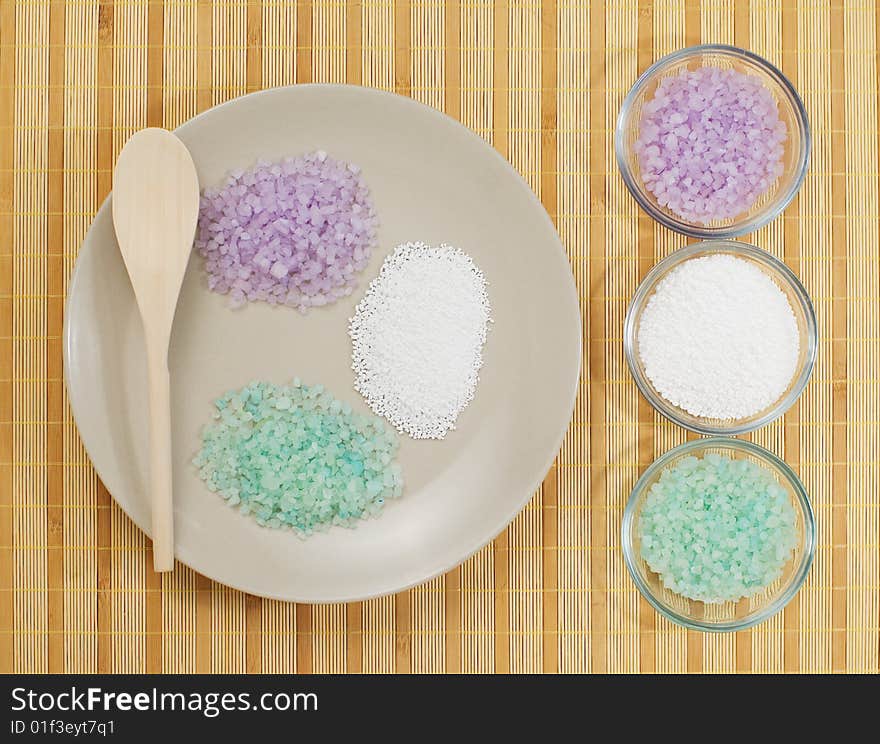 Colorful bath salts on display against a bamboo mat. Colorful bath salts on display against a bamboo mat.