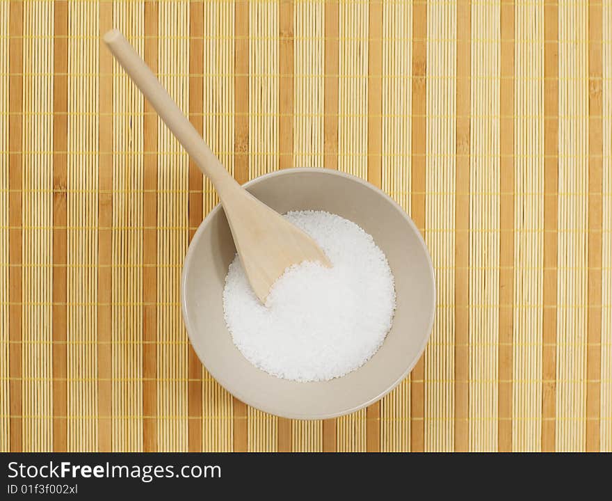 Bowl on a bamboo mat filled with bath salt. Bowl on a bamboo mat filled with bath salt.