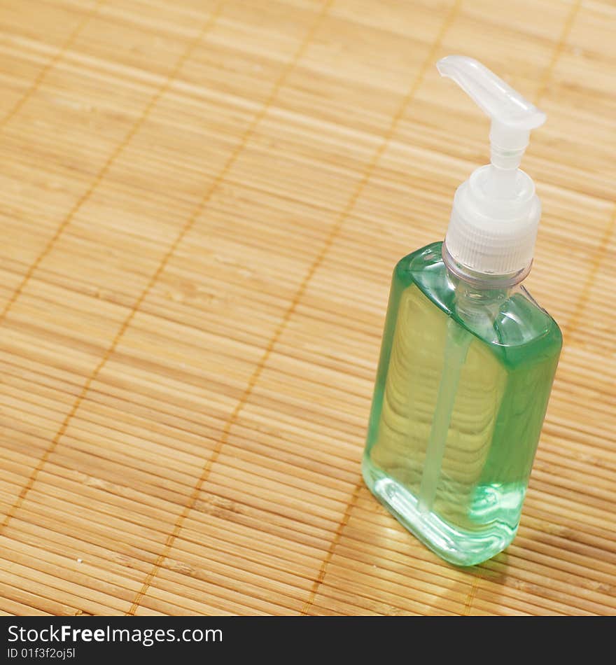 A soap bottle on display against a bamboo mat. A soap bottle on display against a bamboo mat.