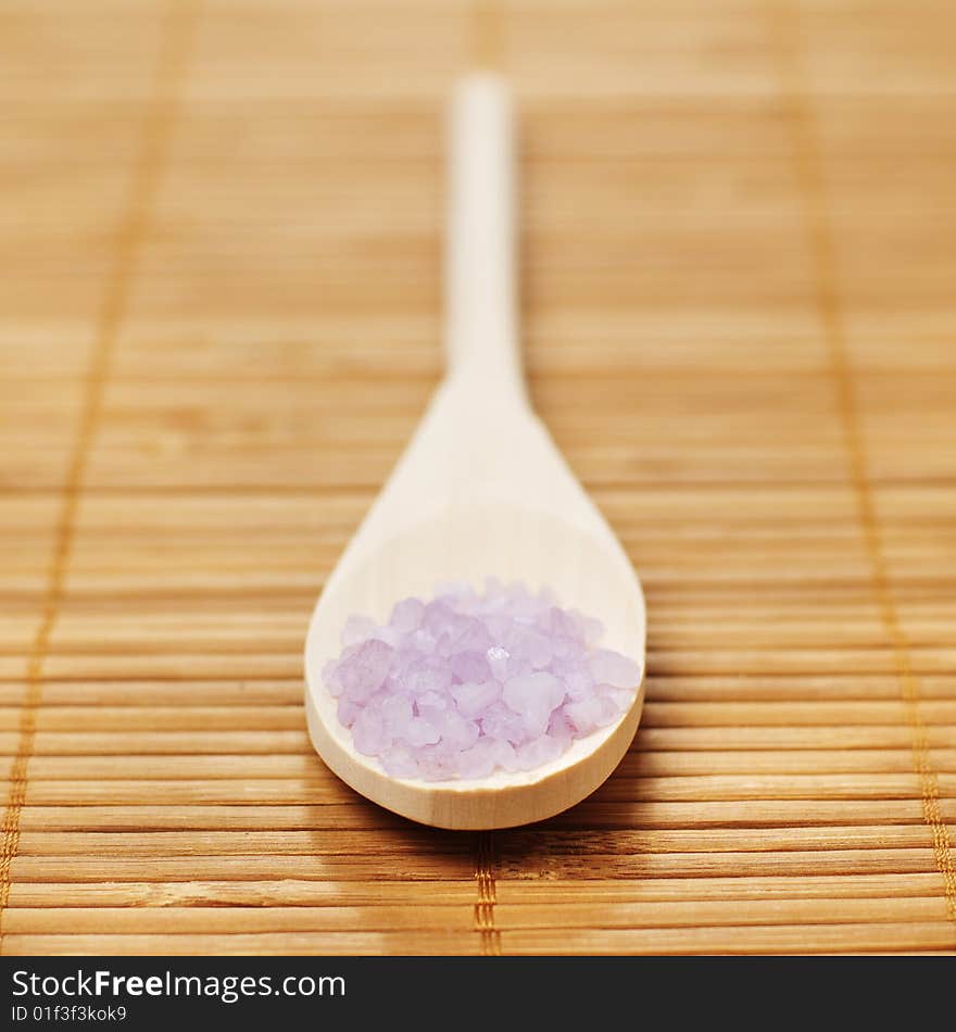 Bath salt and wooden spoon on display against bamboo mat. Bath salt and wooden spoon on display against bamboo mat.