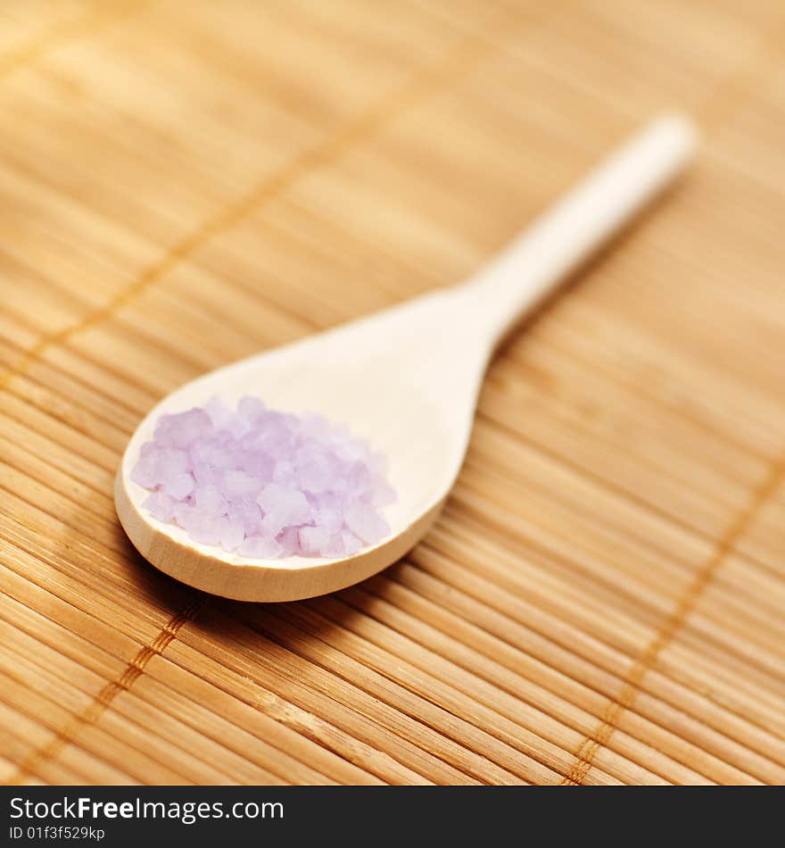 Bath salt and wooden spoon on display against bamboo mat. Bath salt and wooden spoon on display against bamboo mat.