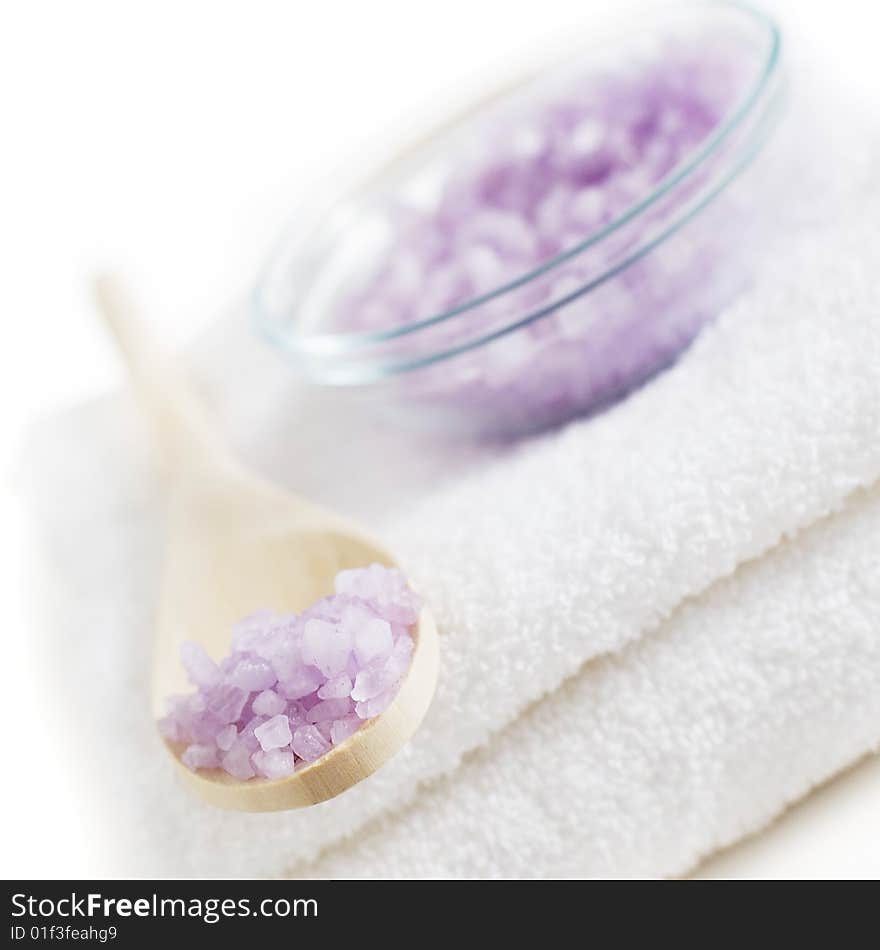 Bowl of bath salt and a wooden spoon on top of white towels. Bowl of bath salt and a wooden spoon on top of white towels.