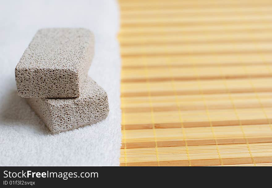 Pumice stones and towel against bamboo reed mat. Pumice stones and towel against bamboo reed mat.