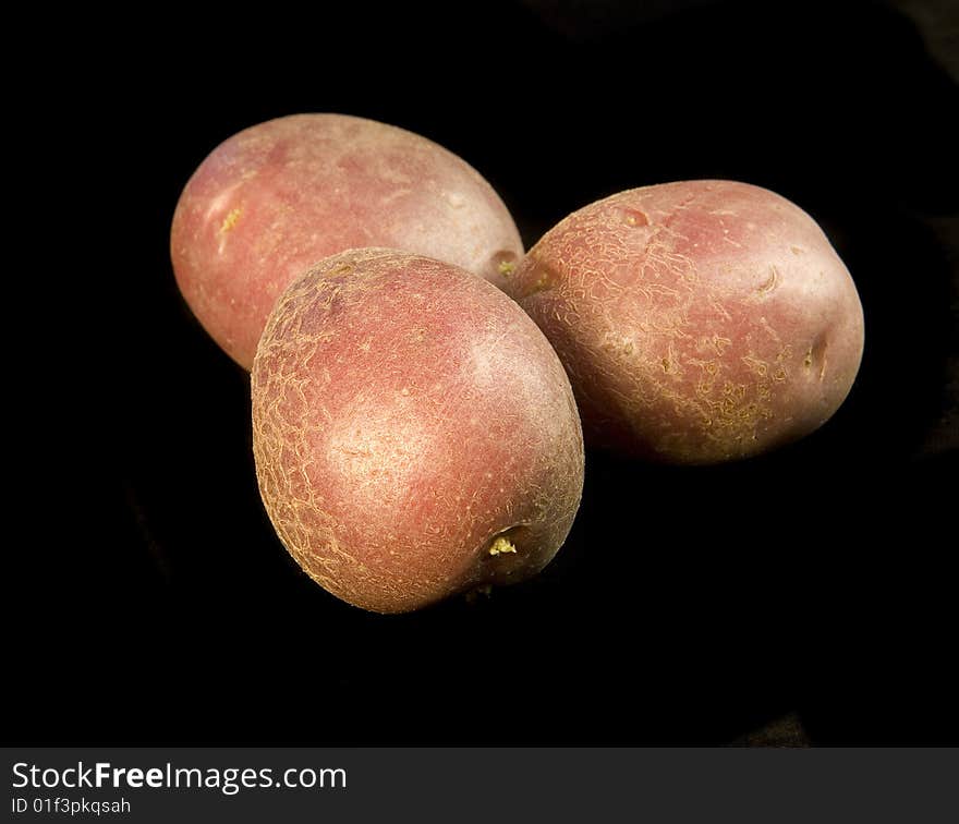 Three potatoes on black ground