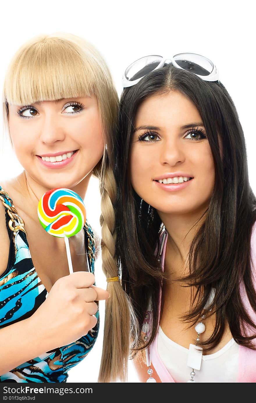 Portrait of two beautiful happy girls with a lollipop against white background