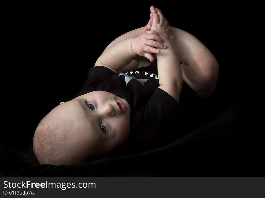 Happy little baby girl with blue eyes isolated on black