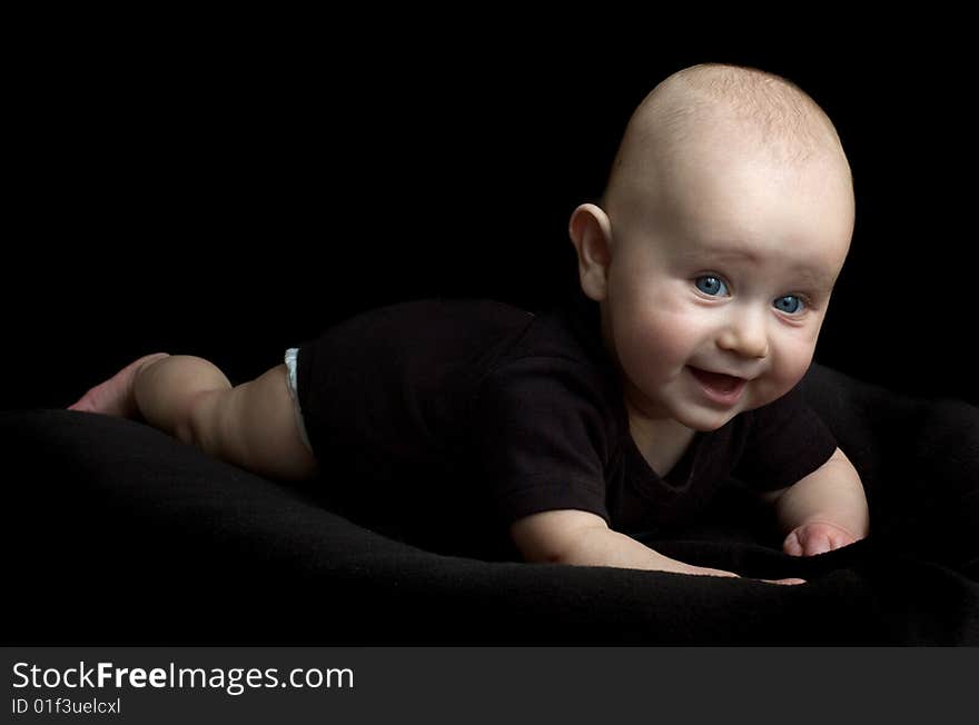 Happy little baby girl with blue eyes isolated on black