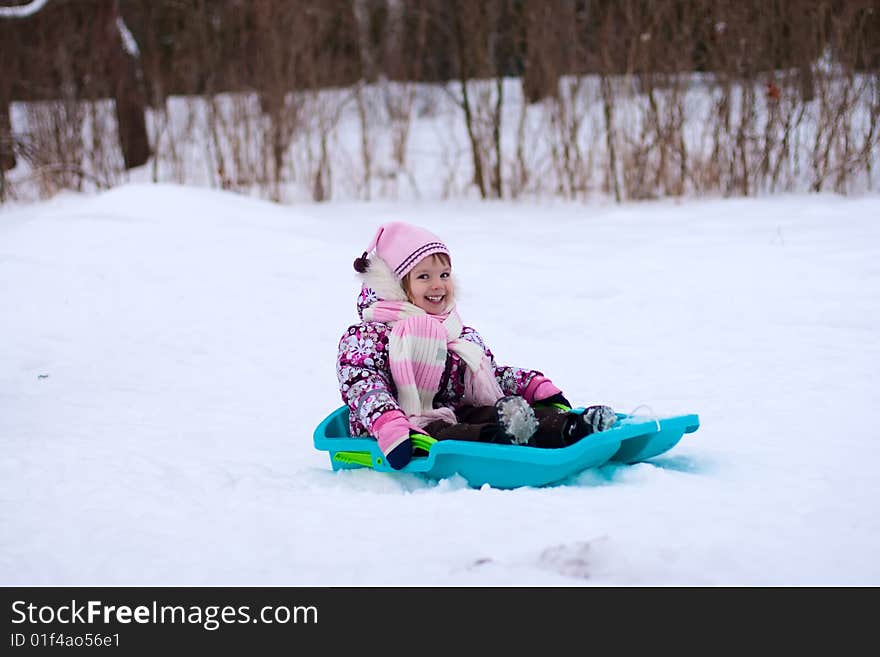 Smileing little girl on sleigh. She laughting.