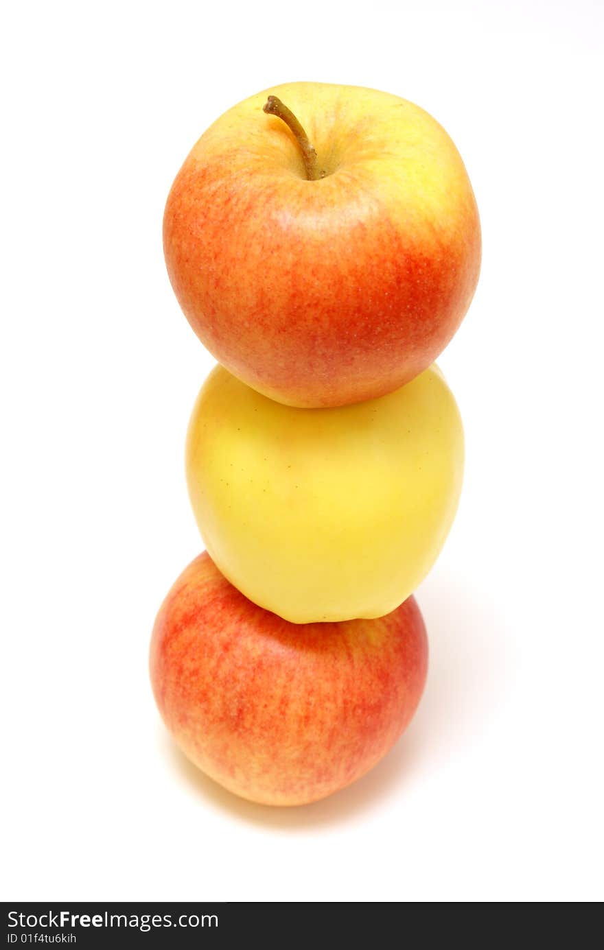 A yellow apple is stuck in the middle of two red ones.