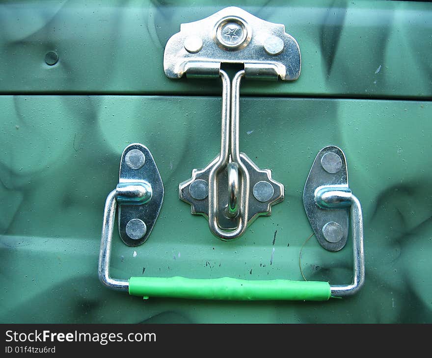 A steel latch and a handle on a green steel trunk