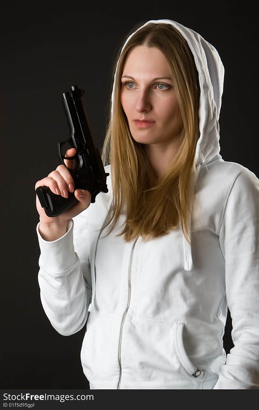 Girl in a white loose overall with gun on a dark background. Girl in a white loose overall with gun on a dark background