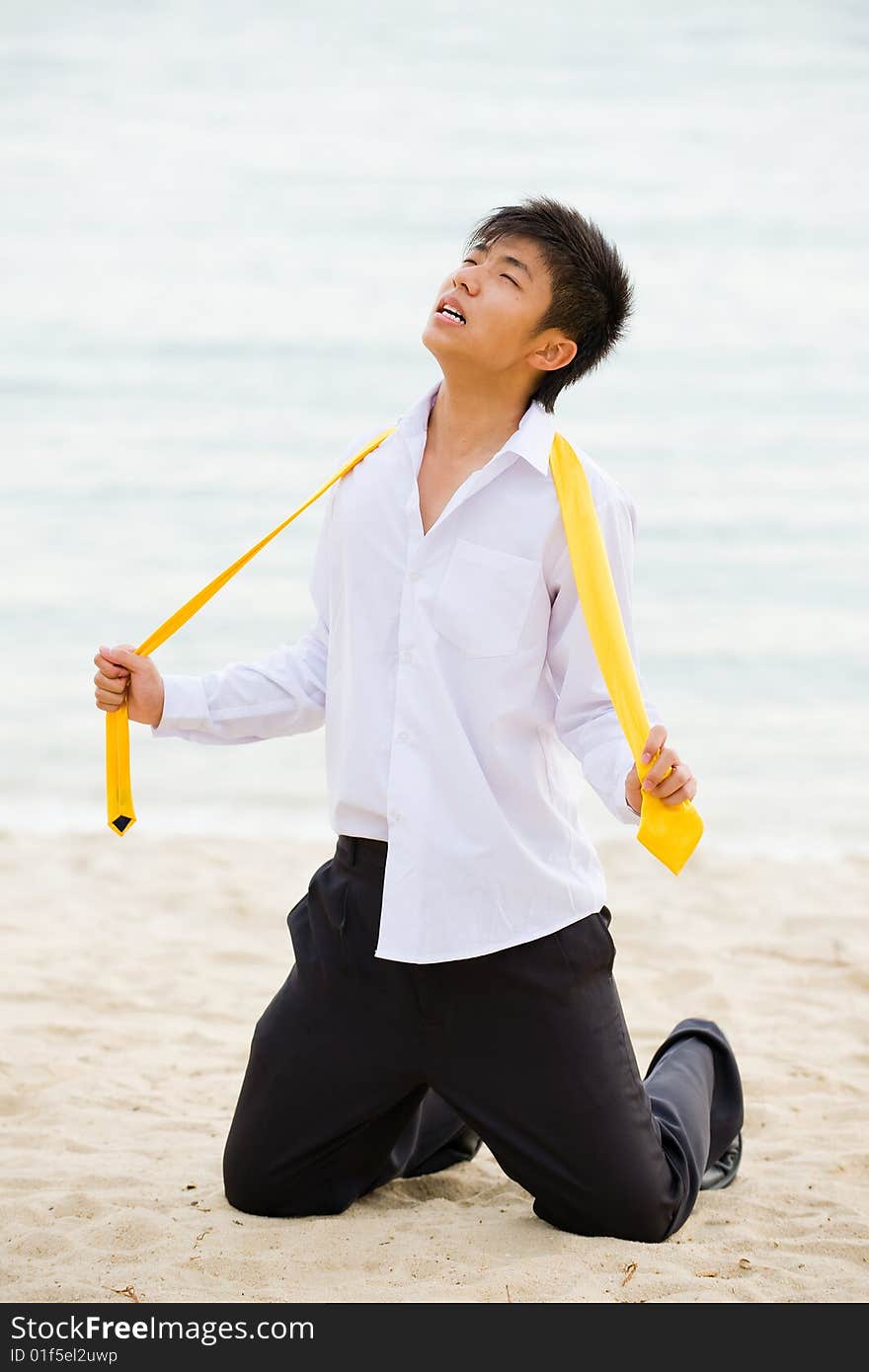 Young business man on his knees at the beach