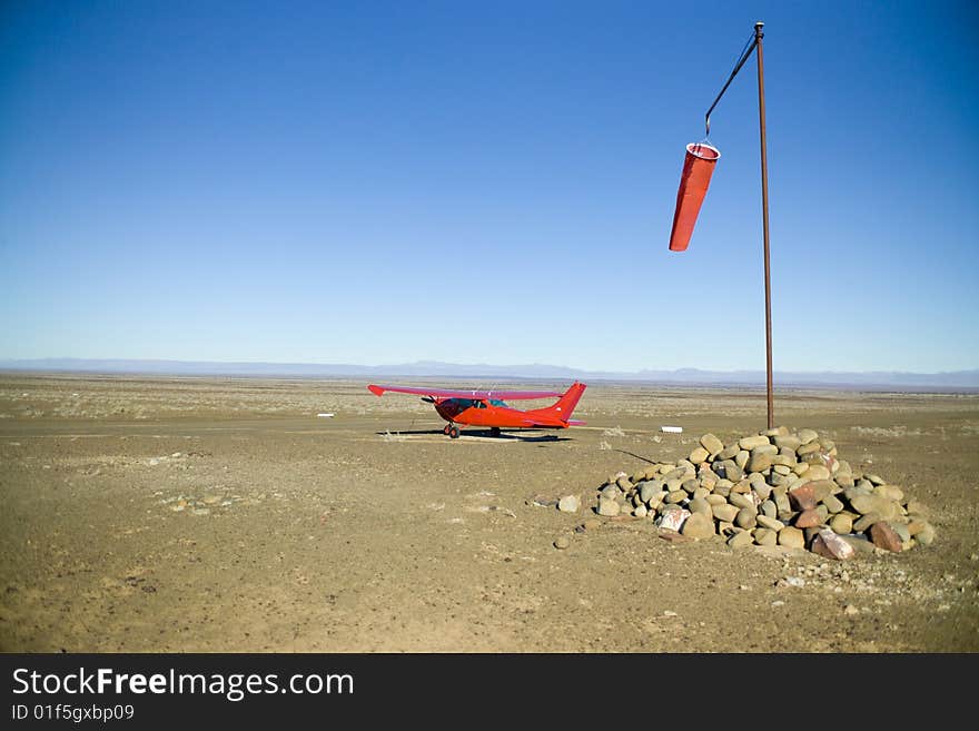 Red airplane waiting on a deserted dirt landing strip in Africa. Red airplane waiting on a deserted dirt landing strip in Africa.