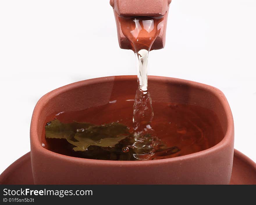 Green tea pouring into tea cup from teapot on white background. Green tea pouring into tea cup from teapot on white background.