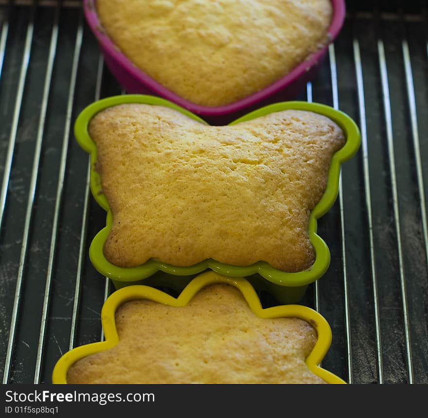 Mini cakes in coloured silicone moulds baking in the oven. Mini cakes in coloured silicone moulds baking in the oven