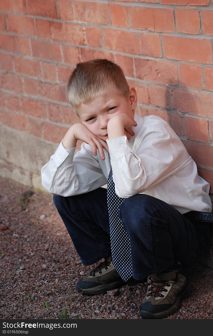 a boy squatting on hams on a background a brick wall, propping up hands person