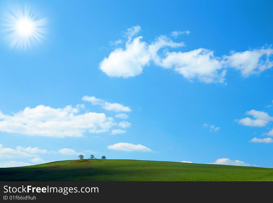 Green field under blue sky with clouds