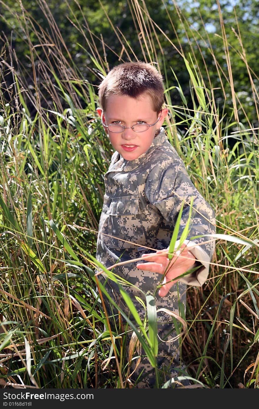 Young boy in camoflauge hiding in the tall grass