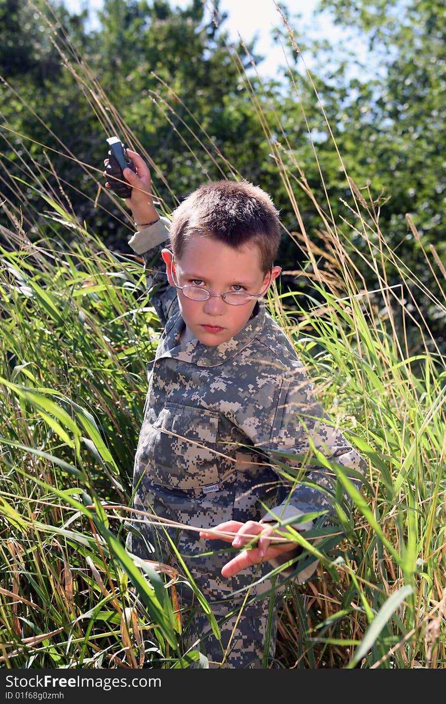 Boy in camoflauge raising arm to throw grenade