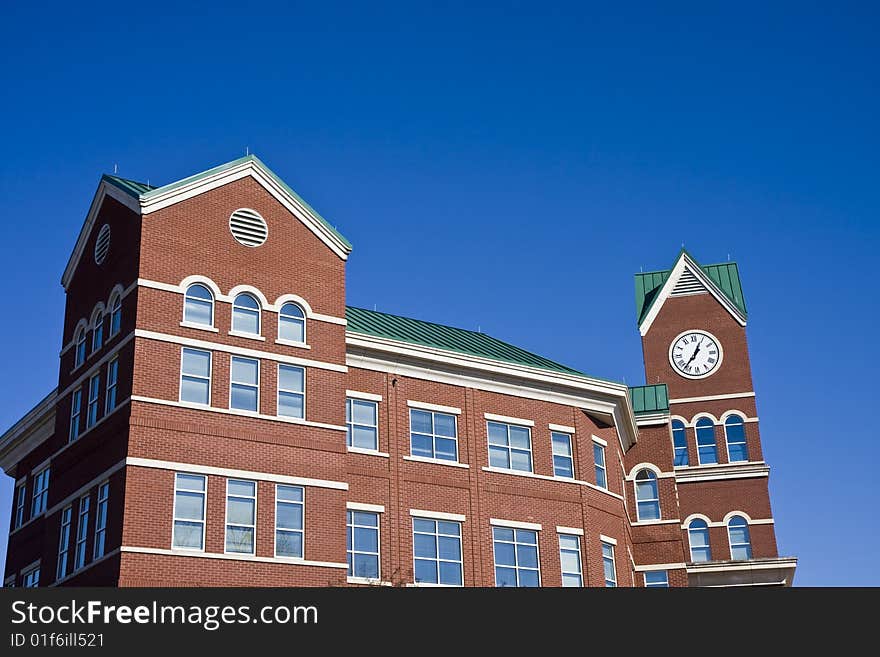 A brick courthouse with a clock against a blue sky. A brick courthouse with a clock against a blue sky