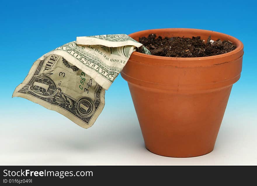 A US $1.00 bill wilting in terra cotta flower pot on graded blue/white background. A US $1.00 bill wilting in terra cotta flower pot on graded blue/white background.