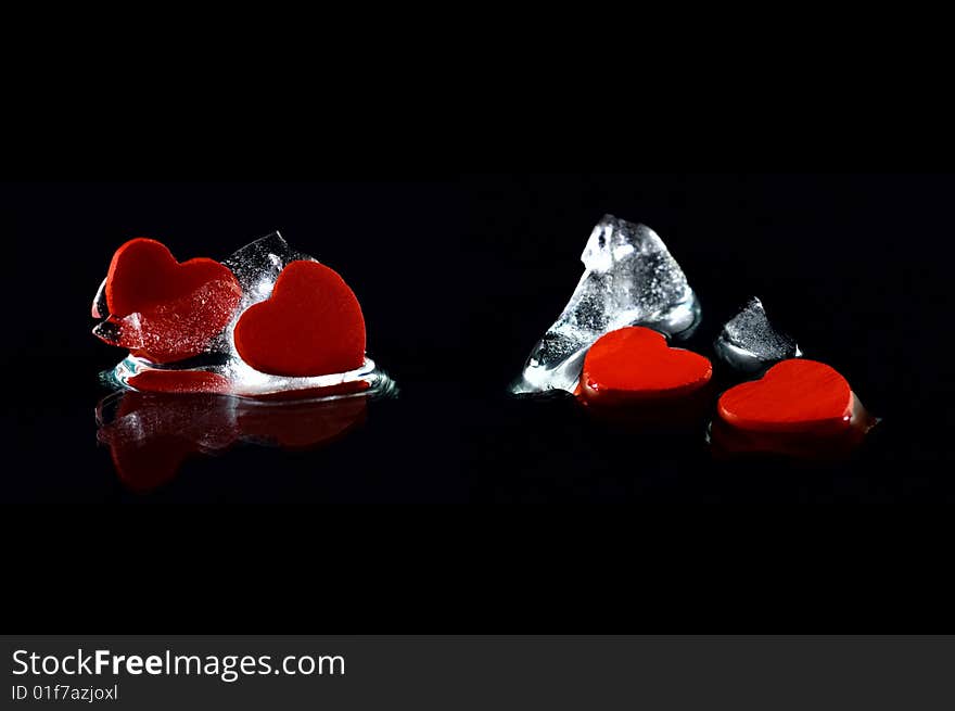 Four hearts in almost melted ice cubes with  reflection on black background. Four hearts in almost melted ice cubes with  reflection on black background