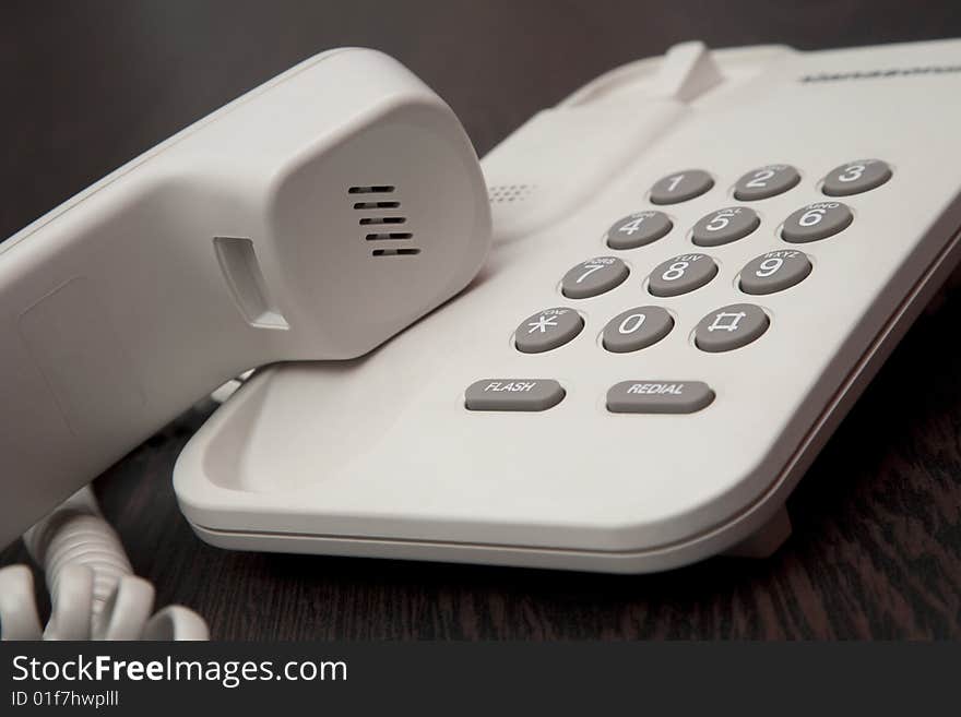 White office phone with a receiver on hold. White office phone with a receiver on hold