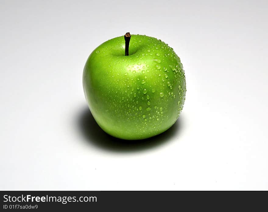 Granny smith apple with droplets of water and a heavy shadow. Granny smith apple with droplets of water and a heavy shadow