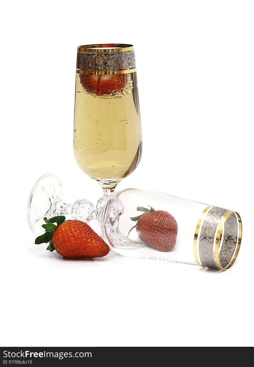 Two glasses with the champagne, decorated with a strawberry. Champagne and a strawberry on a white background. Two glasses with the champagne, decorated with a strawberry. Champagne and a strawberry on a white background.