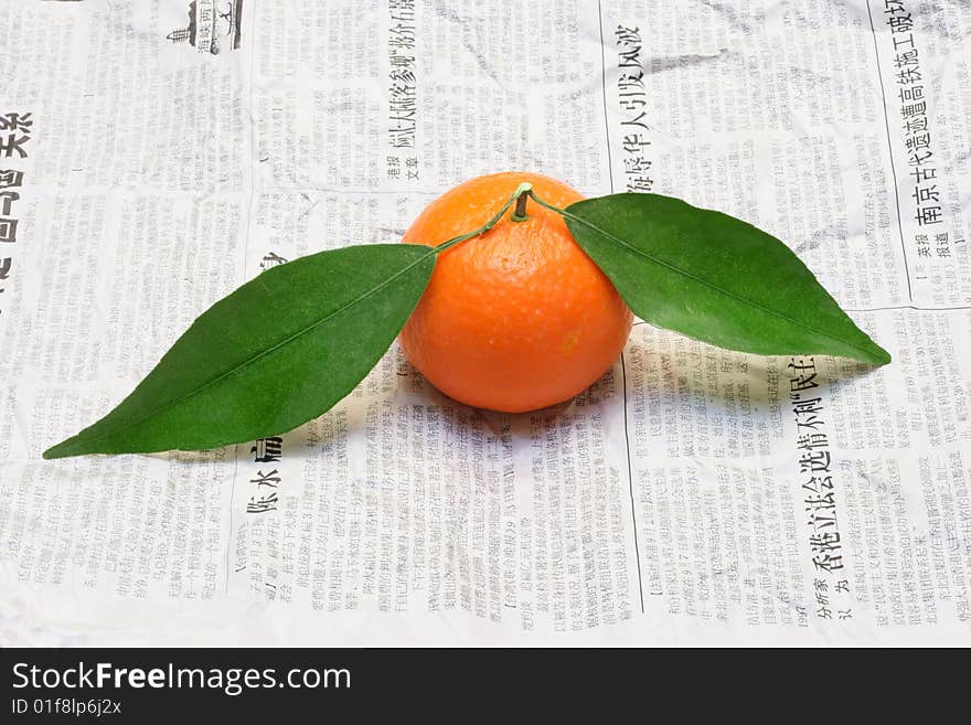 Tangerine with green slip on chinese newspaper