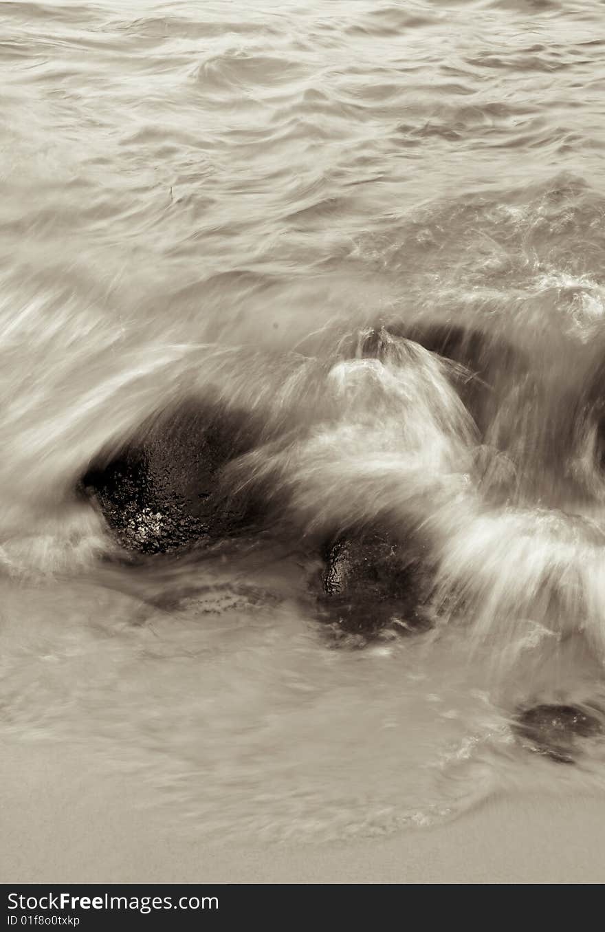 Wave crashing on rocks during the ebbing tide. Wave crashing on rocks during the ebbing tide