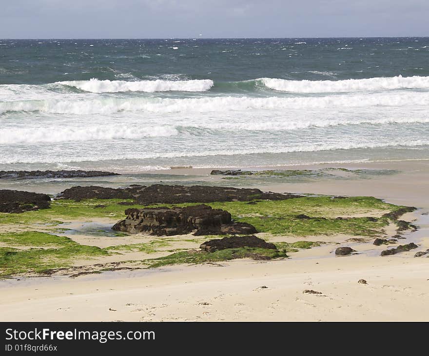 Wild beach and waves crashing on coastal rocks.