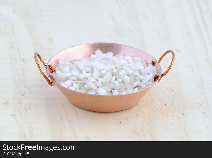 Picture of frying pan isolated in background of wood with rice. Picture of frying pan isolated in background of wood with rice