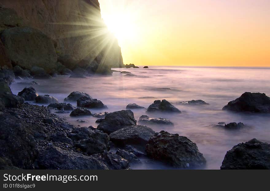 Sunrise at seaside with rock silhouette