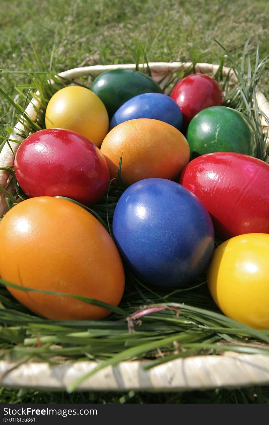 Easter eggs on a bascket with different color on the grass