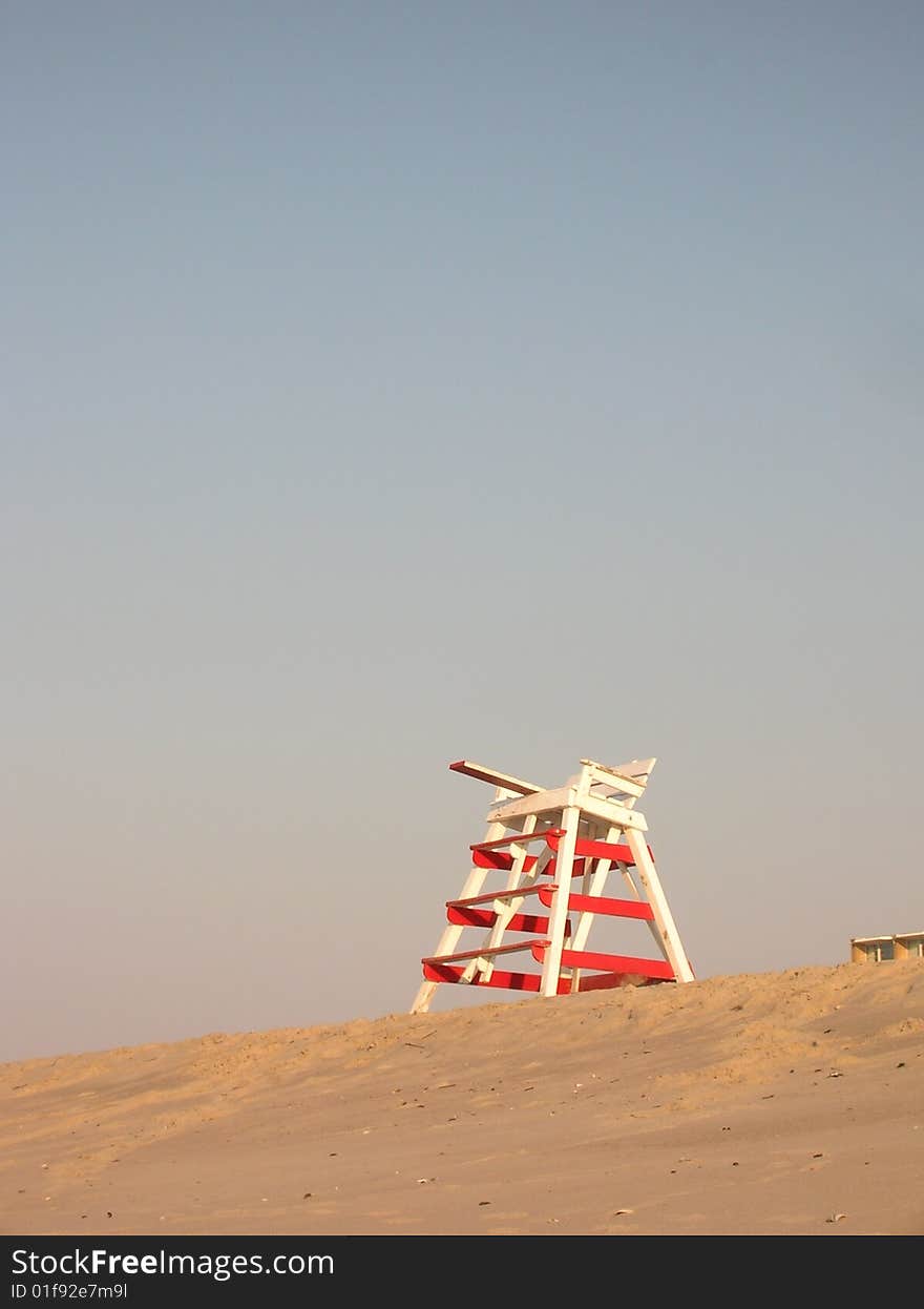 Red and white striped lifeguard stand high up on a sandy dune in the early morning sun Cape May beach. Red and white striped lifeguard stand high up on a sandy dune in the early morning sun Cape May beach