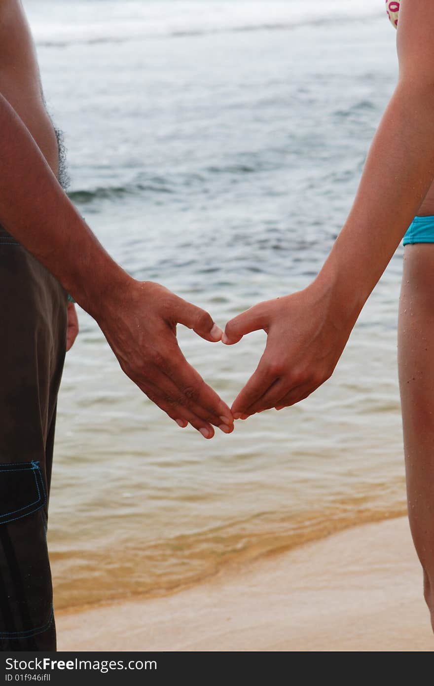 The man and the woman hold hands in the form of a heart, on an ocean coast