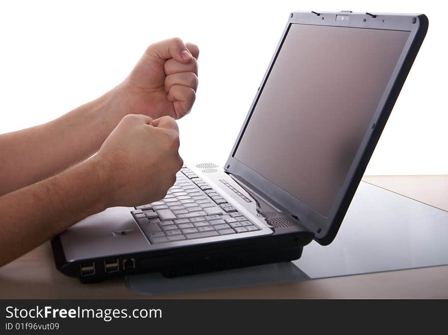 Two fists show anger in front of laptop on a table. Isolated over white background. Copyspace also on the screen. Two fists show anger in front of laptop on a table. Isolated over white background. Copyspace also on the screen.